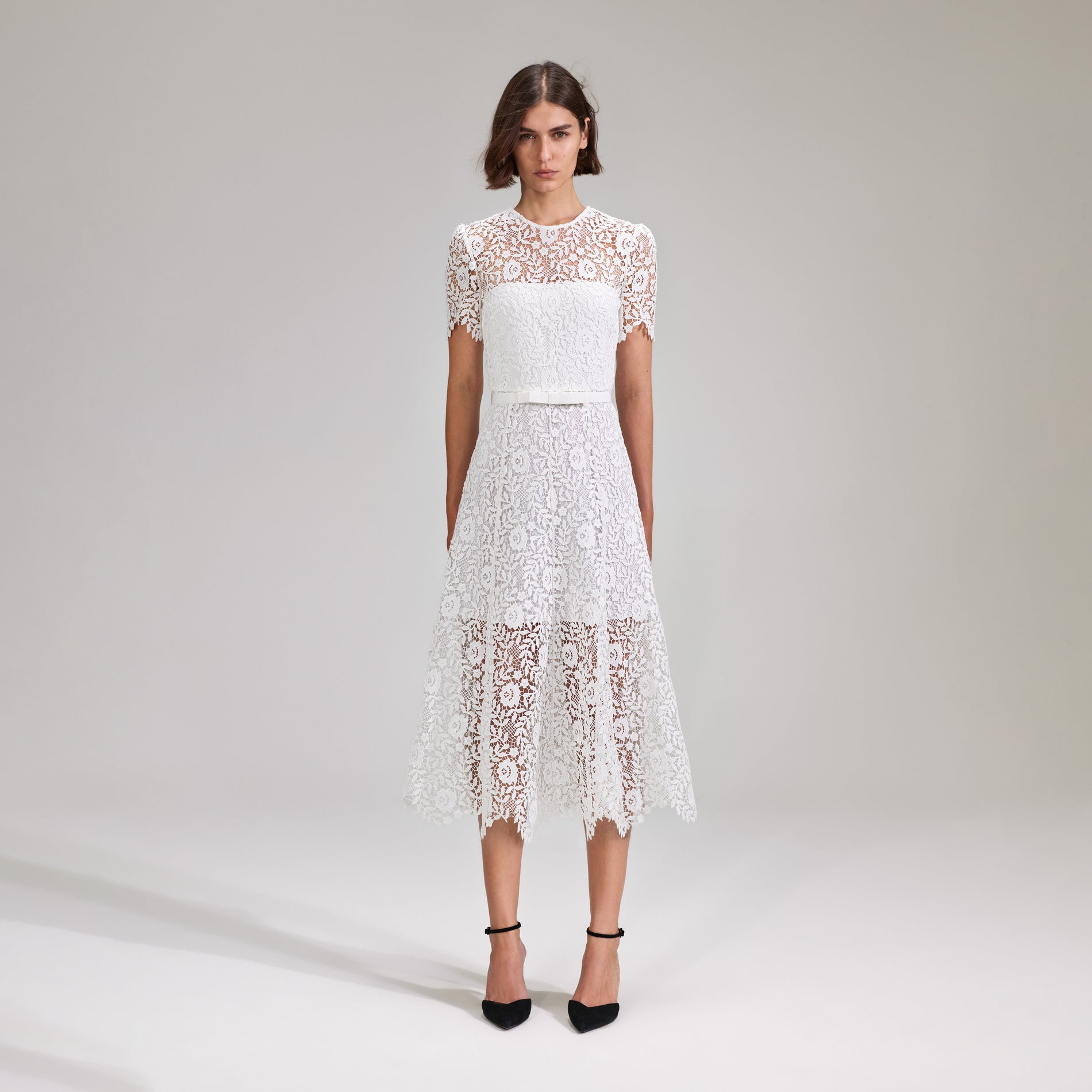 A woman wearing the White Rose Lace Midi Dress