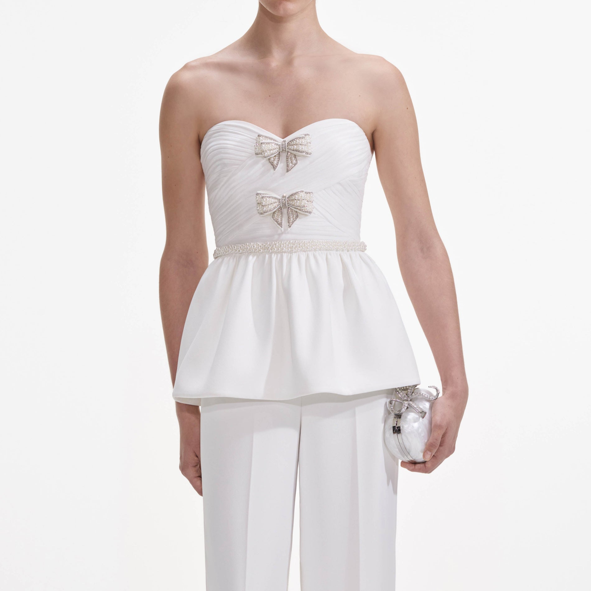A close up of a woman wearing the White Organza Bow Jumpsuit