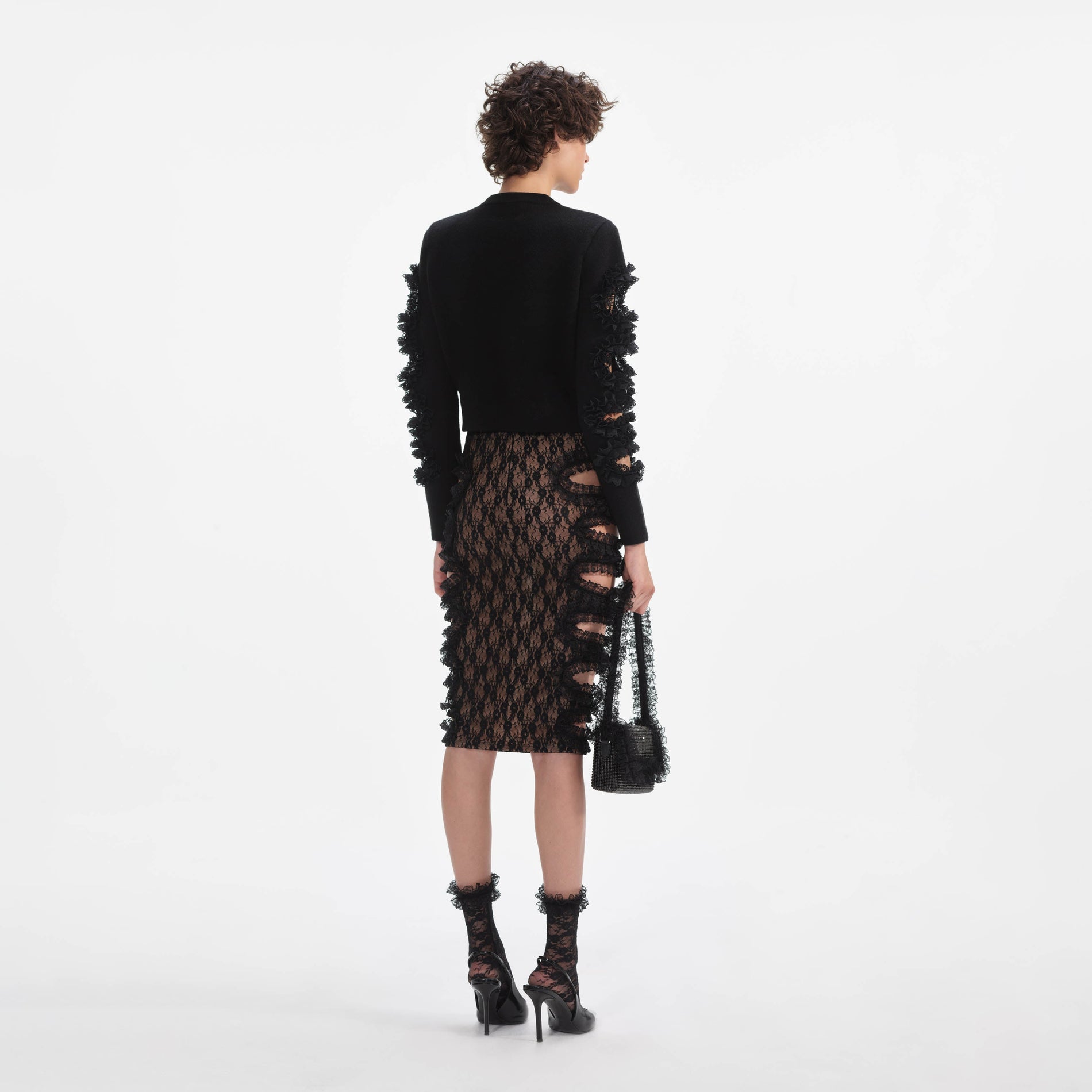 Back view of a woman wearing the Black Lace Cut Out Midi Skirt