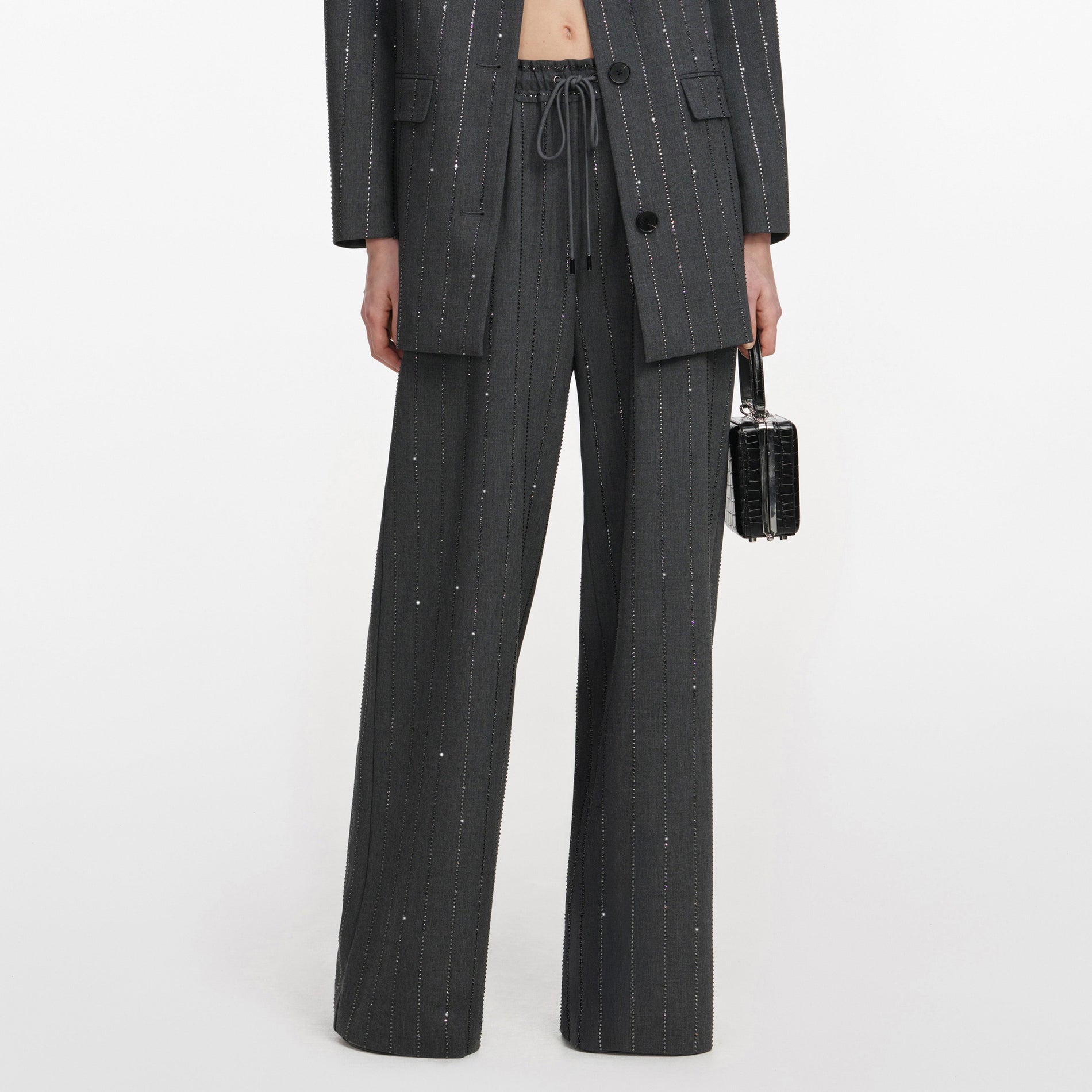 A close up of a woman wearing the Grey Rhinestone Pinstripe Trousers