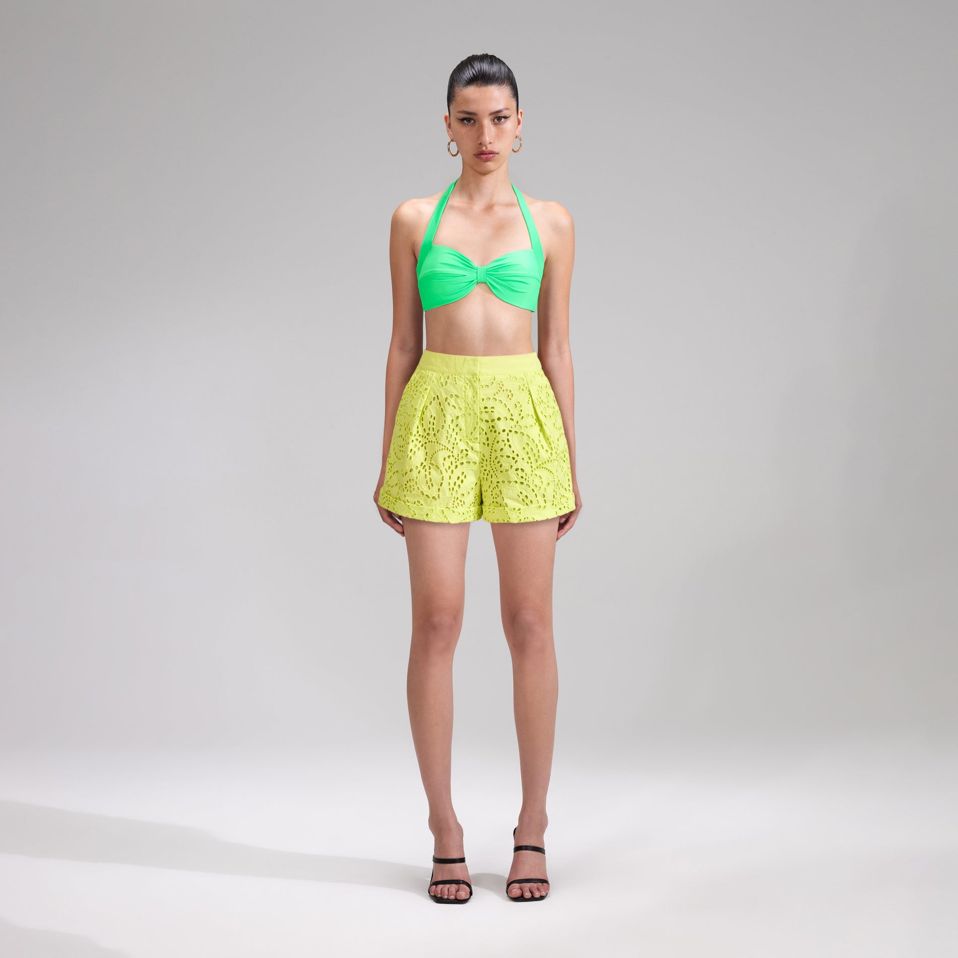 A woman wearing the Lime Broderie Shorts