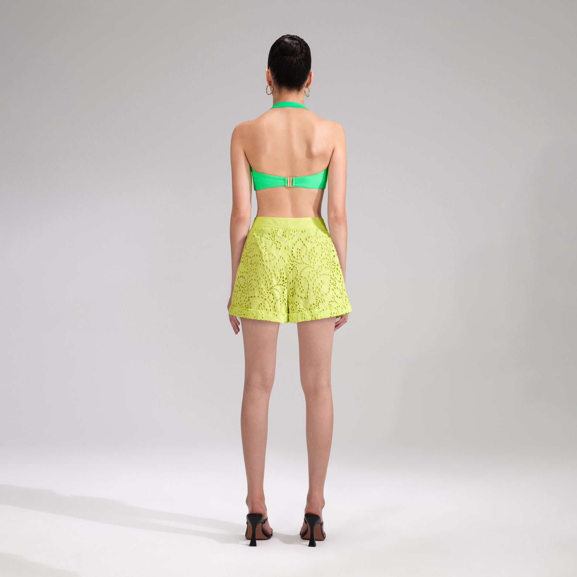 A woman wearing the Lime Broderie Shorts